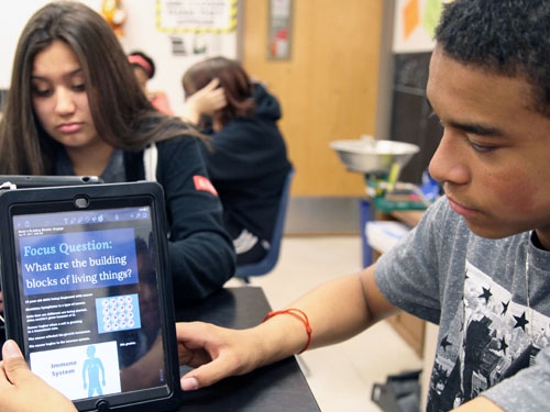 male student holding an iPad that says 