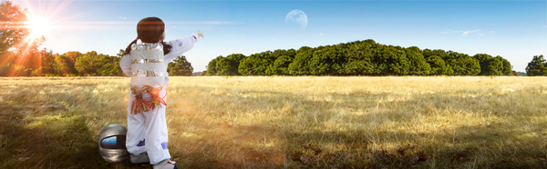 Young girl in an astronaut suit pointing at the moon.